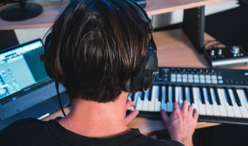 Komposition am MIDI-Keyboard mit Laptop und Kopfhörern im Studio der audiomarketeers